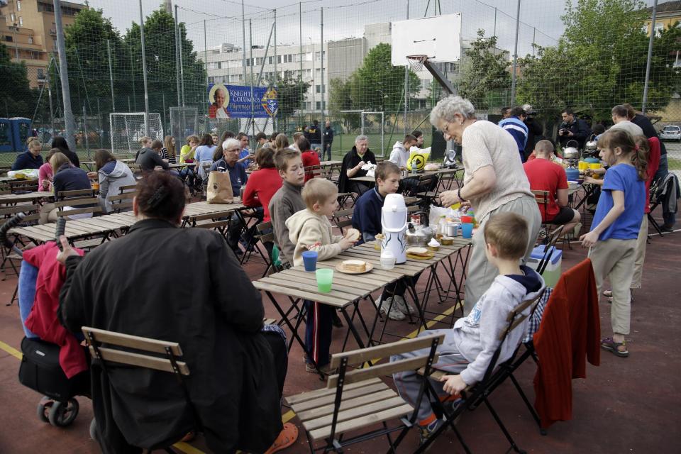Polish pilgrims enjoy their breakfast at a tent camp set up at Knights Columbus sports grounds in Rome, Saturday, April 26, 2014. Hundred thousands of pilgrims and faithful are expected to reach Rome to attend the scheduled April 27 ceremony at the Vatican in which Pope Francis will elevate in a solemn ceremony John XXIII and John Paul II to sainthood. (AP Photo/Gregorio Borgia)