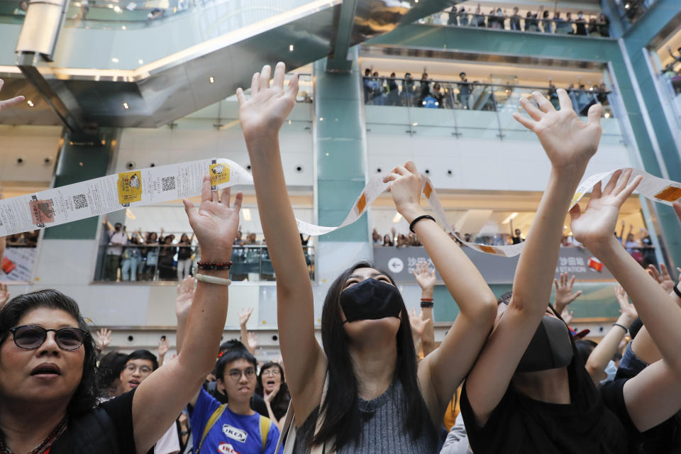 Protesters grab queuing tickets hanging from several floors above issued by a restaurant owned by a pro-Beijing company inside a shopping mall at the Sha Tin district in Hong Kong Sunday, Sept. 22, 2019. Young protesters, many wearing masks to disguise their identity, filled the open area of a Hong Kong shopping mall Sunday and folded paper "origami" cranes in the latest twist in a pro-democracy movement that has stretched into a fourth month. (AP Photo/Kin Cheung)