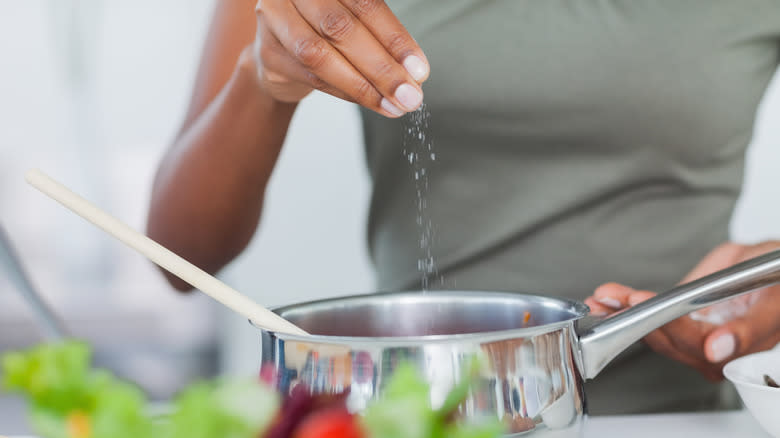 adding a pinch of salt to a pot