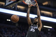 Sacramento Kings forward Marvin Bagley III hangs from the rim after dunking against the Utah Jazz during the first quarter of an NBA basketball game in Sacramento, Calif., Friday, Oct. 22, 2021. (AP Photo/Jose Luis Villegas)