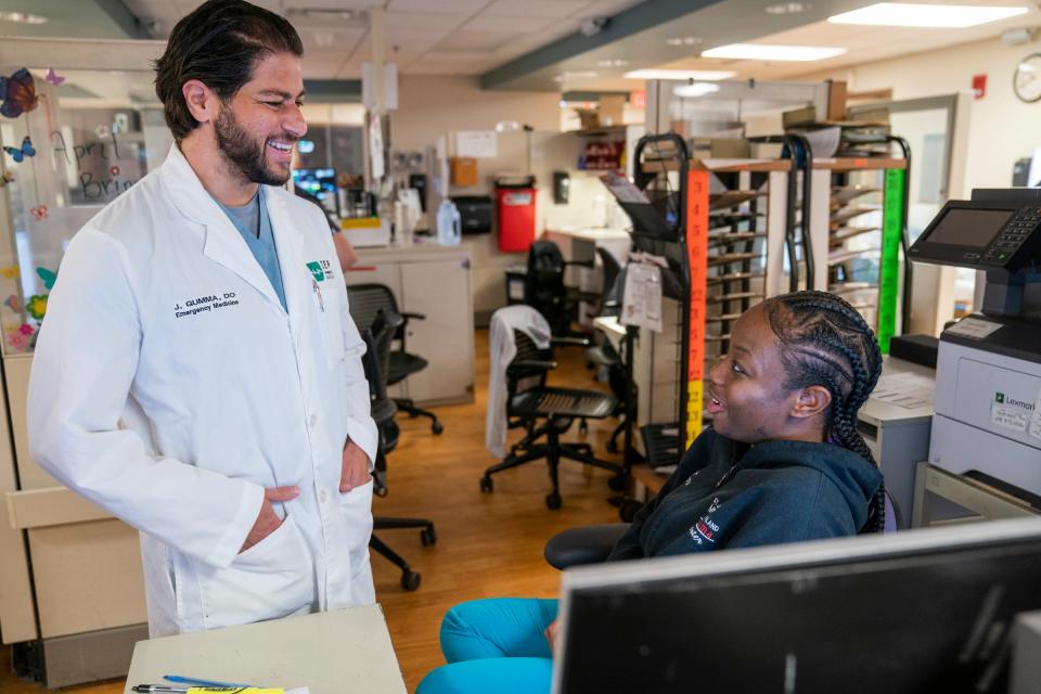 Emergency room Dr. Jason Gumma stops to talk to ER clerk Kenya Fair during their shift at Trinity Health Oakland Hospital in Pontiac on April 21, 2023. They have relaxed their masking mandates for staff and patients.