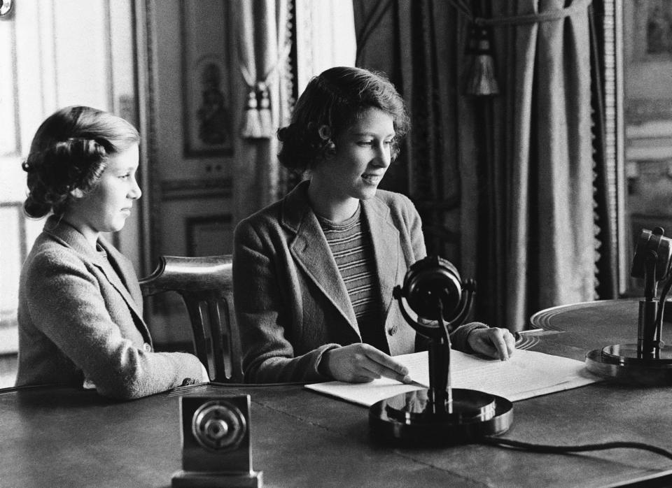 FILE - Britain's Princess Elizabeth, right, 14-year-old heiress apparent to the British throne, broadcasts a three-minute speech to British girls and boys evacuated overseas, in London, Oct. 22, 1940. Her sister Margaret is at left. Queen Elizabeth II will mark 70 years on the throne Sunday, Feb. 6, 2022, an unprecedented reign that has made her a symbol of stability as the United Kingdom navigated an age of uncertainty. (AP Photo, File)