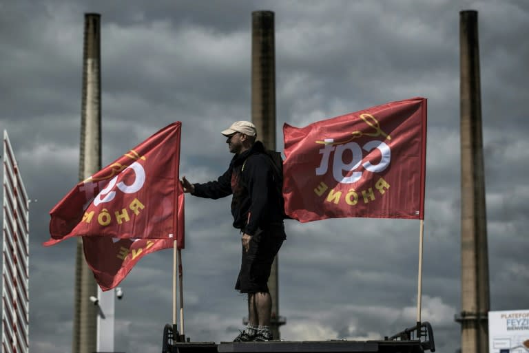 A striking worker stands next to French CGT union flags in front of the Total oil refinery of Feyzin, near Lyon, central-eastern France, on May 24, 2016, during a strike to protest against government labour reforms