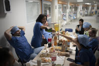 Nurse Bess Tribout, center, pours champagne to celebrate the new year in the COVID-19 intensive care unit at the la Timone hospital in Marseille, southern France, Saturday, Jan. 1, 2022. (AP Photo/Daniel Cole)