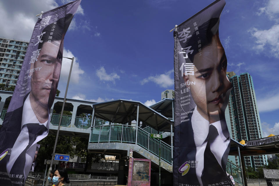 FILE - In this July 11, 2020, file photo, a woman walks past banners of pro-democracy candidates outside a subway station in Hong Kong, in an unofficial primary for pro-democracy candidates ahead of legislative elections. About 50 Hong Kong pro-democracy figures were arrested by police on Wednesday, Jan. 6, 2021 under a national security law, following their involvement in an unofficial primary election last year held to increase their chances of controlling the legislature, according to local media reports. (AP Photo/Vincent Yu, File)