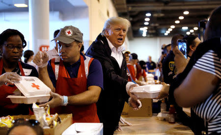 U.S. President Donald Trump helps volunteers hand out meals during a visit with flood survivors of Hurricane Harvey at a relief center in Houston, Texas, U.S., September 2, 2017. REUTERS/Kevin Lamarque