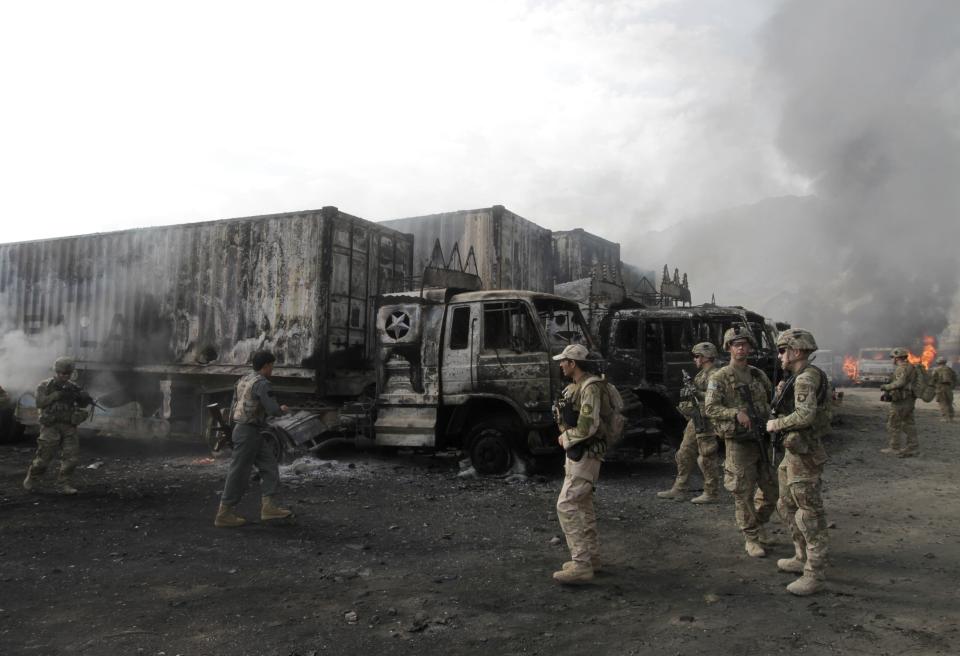 NATO troops walk near burning NATO supply trucks after, what police officials say, was an attack by militants in the Torkham area near the Pakistani-Afghan in Nangarhar Province June 19, 2014. (REUTERS/ Parwiz)