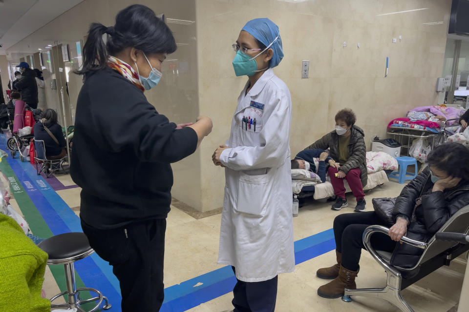A medical worker talks to a woman as elderly patients receive intravenous drips along a corridor in the emergency ward of a hospital in Beijing, Thursday, Jan. 5, 2023. Patients, most of them elderly, are lying on stretchers in hallways and taking oxygen while sitting in wheelchairs as COVID-19 surges in China's capital Beijing. (AP Photo/Andy Wong)