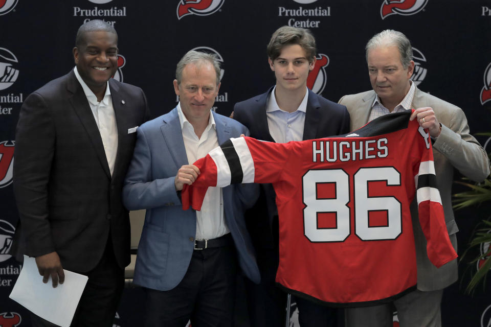 New Jersey Devils forward Jack Hughes, center right, the No. 1 overall pick in the 2019 NHL draft, poses for photographers with former NHL player Kevin Weekes, far left, Josh Harris, second from left, managing partner of Harris Blitzer Sports & Entertainment, and Ray Shero, Devils executive vice president and general manager, during a news conference introducing the prospect to local media, Tuesday, June 25, 2019, in Newark, N.J. (AP Photo/Julio Cortez)