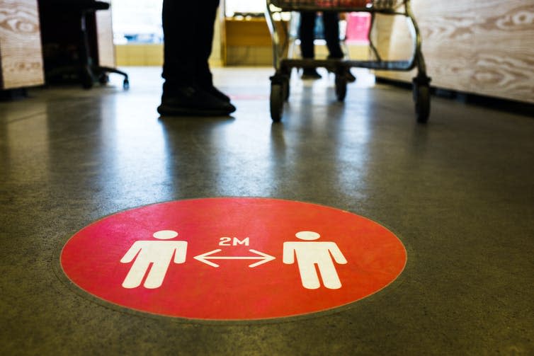 A sign on a supermarket floor promoting social distancing