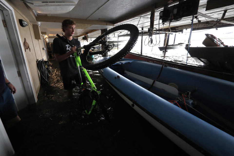 Rudy Horvath Jr. moves his bicycle from his home, a boat house in the West End section of New Orleans, after it took on water from a rising storm surge from Lake Pontchartrain in advance of Tropical Storm Cristobal, Sunday, June 7, 2020. (AP Photo/Gerald Herbert)