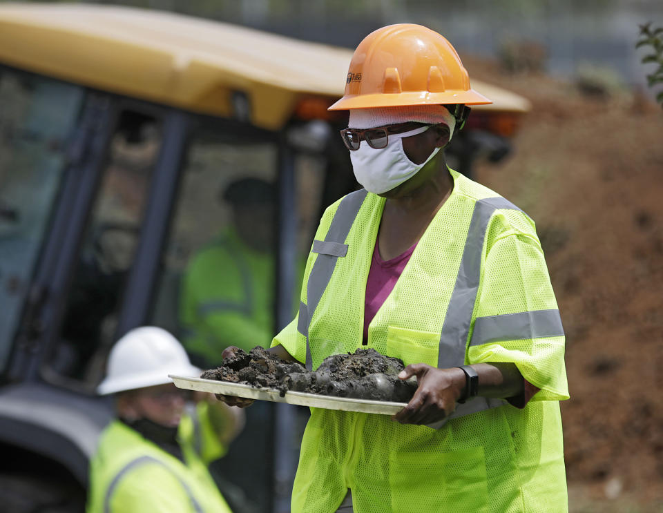 FILE - In this July 21, 2020, file photo, forensic anthropologist Phoebe Stubblefield carries a tray of items found at Oaklawn Cemetery during a test excavation in the search for possible mass graves from the 1921 Tulsa Race Massacre in Tulsa, Okla. A second excavation begins Monday, Oct. 19, 2020 at a Tulsa cemetery in search of people killed in the massacre in an effort to identify the victims and shed light on the violence. (Mike Simons/Tulsa World via AP File)