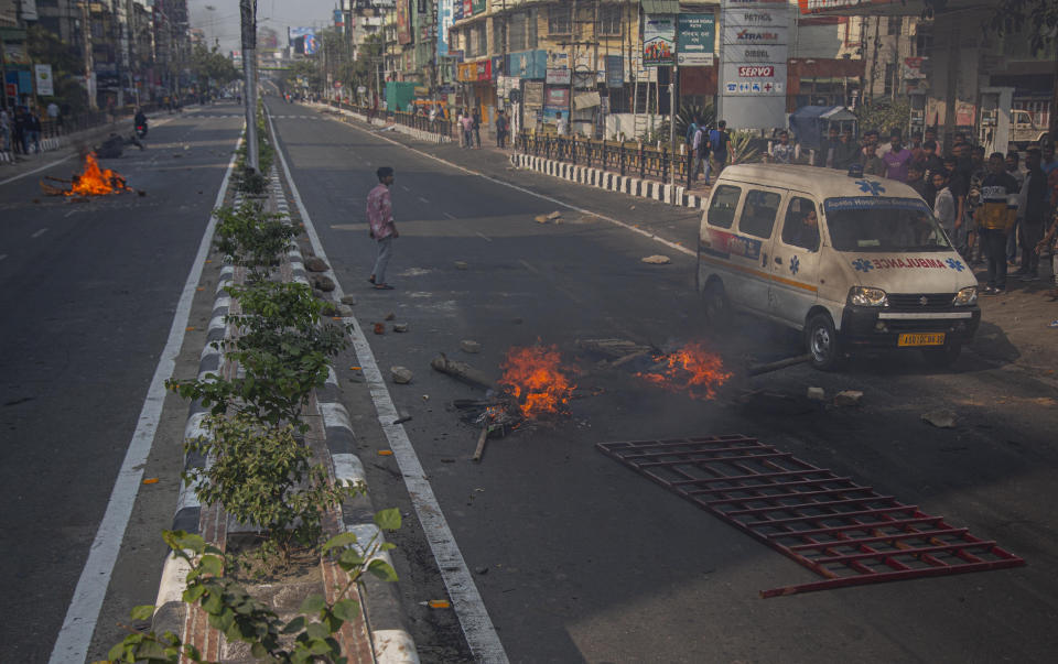 An ambulance drives past fire set by protestors to block traffic in Gauhati, India, Thursday, Dec. 12, 2019. Police arrested dozens of people and enforced curfew on Thursday in several districts in India’s northeastern Assam state where thousands protested legislation granting citizenship to non-Muslims who migrated from neighboring countries. (AP Photo/Anupam Nath)