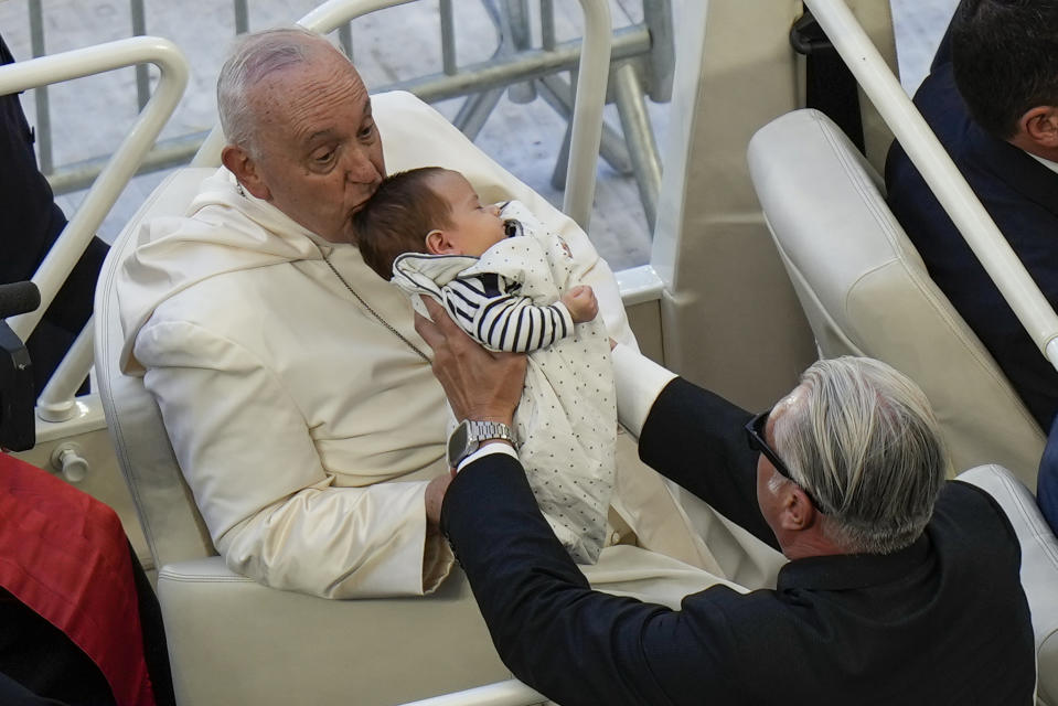 Pope Francis kisses a baby as he arrives at the "Velodrome Stadium", in Marseille, France, to celebrate mass, Saturday, Sept. 23, 2023. Francis, during a two-day visit, will join Catholic bishops from the Mediterranean region on discussions that will largely focus on migration. (AP Photo/Pavel Golovkin)