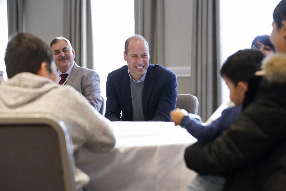 Prince William, Duke of Cambridge (C) smiles as he talks with refugees evacuated from Afghanistan during a visit to a hotel in Leeds