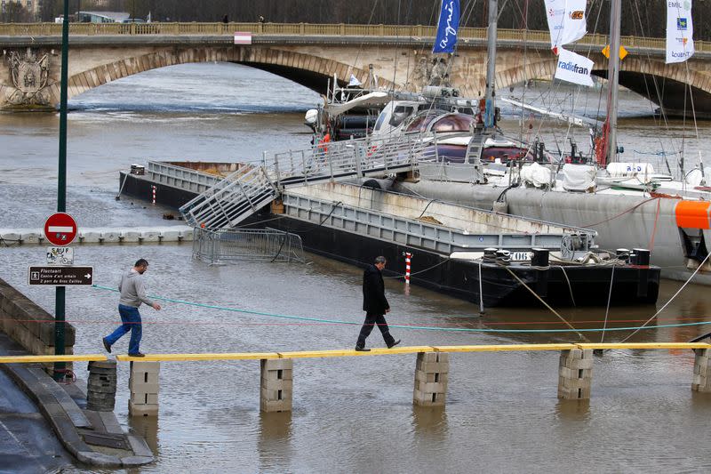 People walk on a plank bridge on the flooded river-side of river Seine as water levels are expected to hit 4.3 metres today in Paris