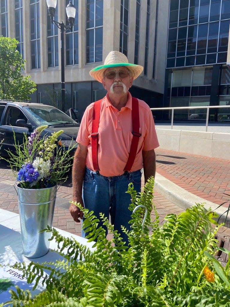 Dean Fallis, 75, owner of Bloomers Greenhouse in West Point, Indiana, stands with his cut flowers at the Indianapolis Original Farmers’ Market on Market Street on May 31, 2023. He brings flowers and produce to seven markets a week, four of which take place on Saturdays.