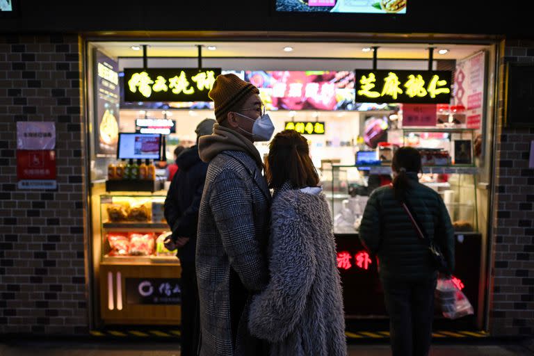 Un grupo de personas con barbijo frente a una tienda en el distrito de Huangpu, en Shanghai, el 19 de diciembre de 2022. 