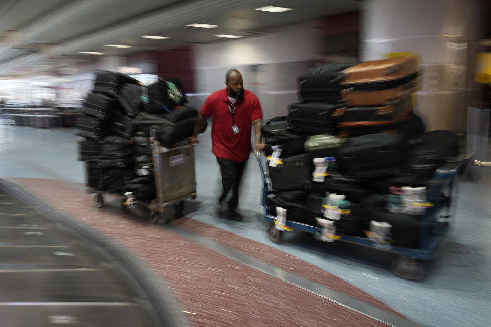Leo Stevens, a baggage handler at Harry Reid International Airport, helps move bags belonging to the New York Liberty WNBA basketball team, Wednesday, June 28, 2023, in Las Vegas. (AP Photo/John Locher)