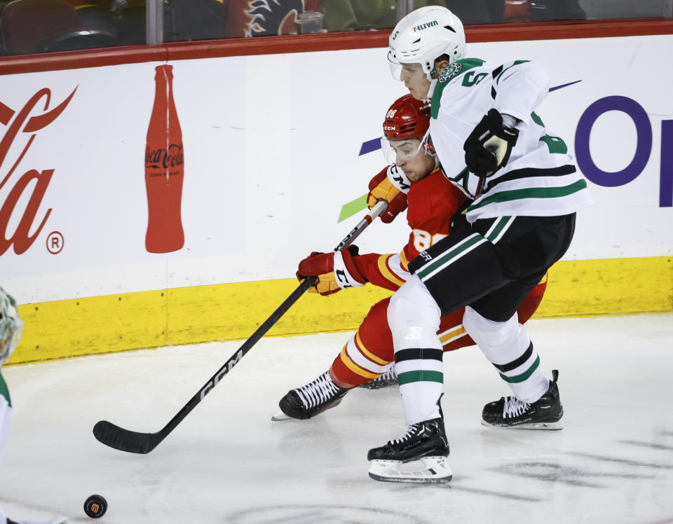 Dallas Stars defenseman Nils Lundkvist, right, checks Calgary Flames forward Andrew Mangiapane during the third period of an NHL hockey game, Wednesday, Nov. 1, 2023 in Calgary, Alberta. (Jeff McIntosh/The Canadian Press via AP)