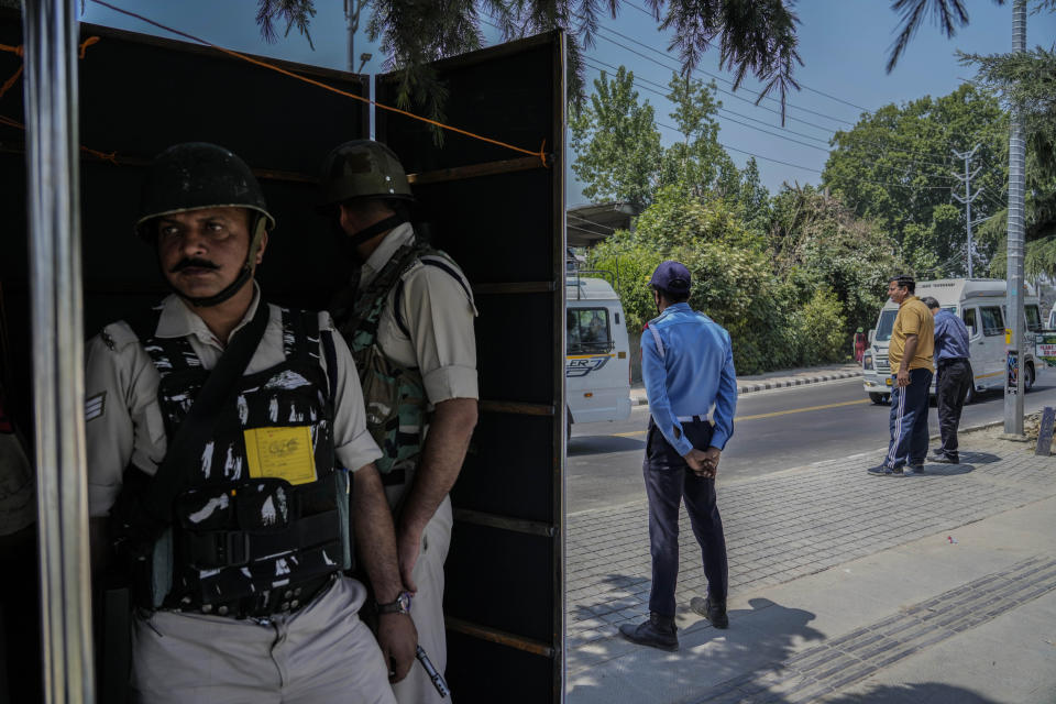 Indian paramilitary soldiers and policemen guard from behind a temporary security post as delegates from the Group of 20 nations arrive to participate in a tourism meeting in Srinagar, Indian controlled Kashmir, Monday, May 22, 2023. The meeting scheduled for later Monday is the first significant international event in Kashmir since New Delhi stripped the Muslim-majority region of semi-autonomy in 2019. (AP Photo/Mukhtar Khan)