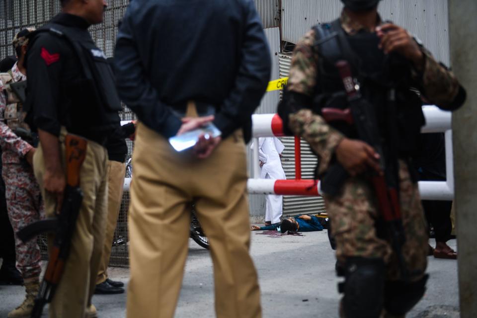 EDITORS NOTE: Graphic content / Police and paramilitary soldiers guard near a body of an alleged gunman at the main entrance of the Pakistan Stock Exchange building in Karachi on June 29, 2020. - Gunmen attacked the Pakistan Stock Exchange in Karachi on June 29, with four of the assailants killed, police said. (Photo by Asif HASSAN / AFP) (Photo by ASIF HASSAN/AFP via Getty Images)