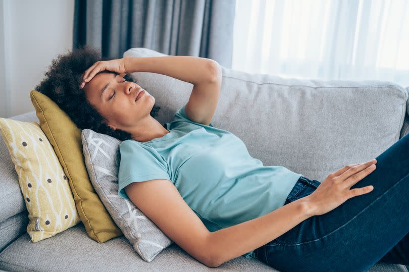 A sick young woman holding her head with hand.