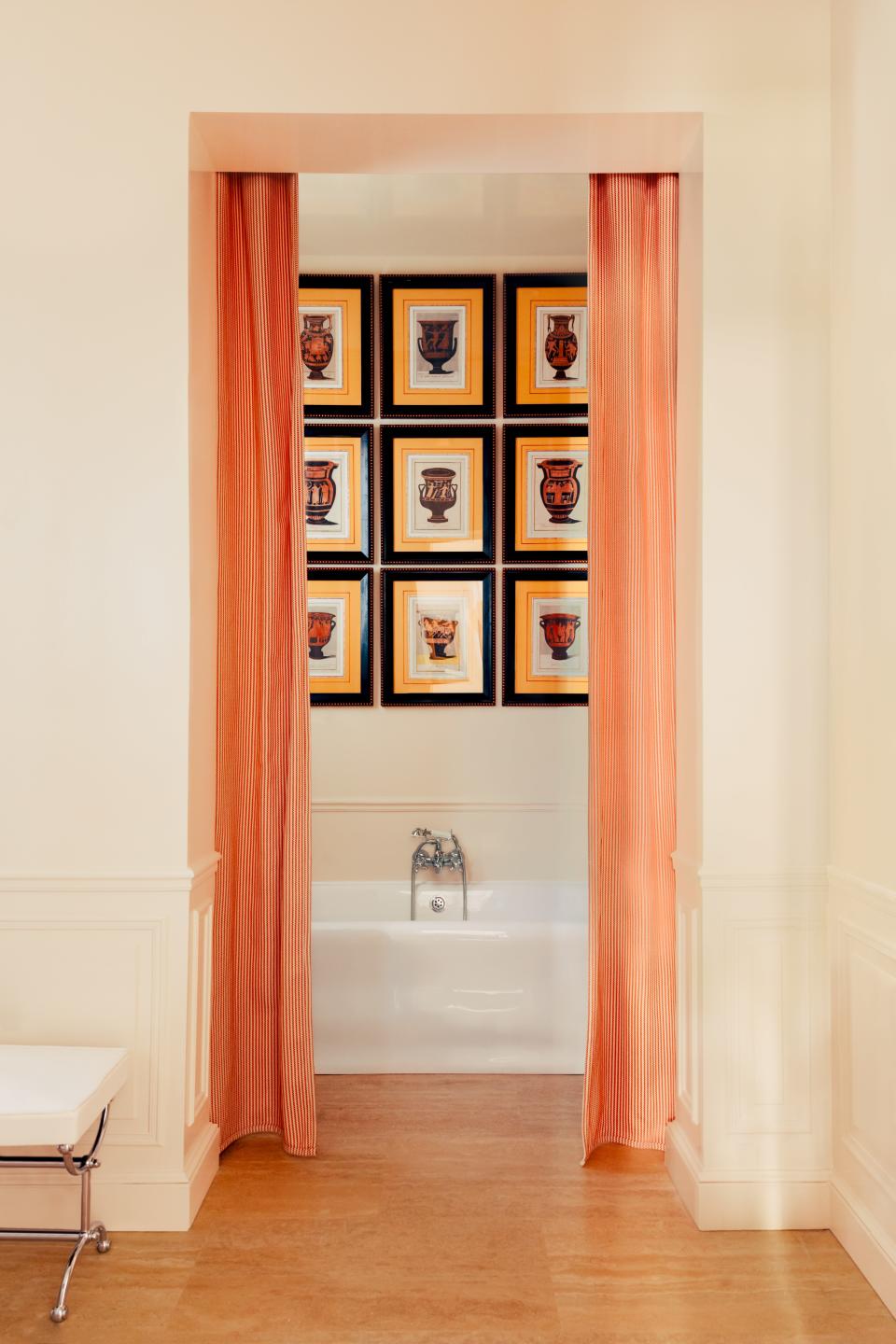 In the master bath, 19th-century prints hang above The Water Monopoly tub. The striped curtains are made of an outdoor fabric by Dedar.