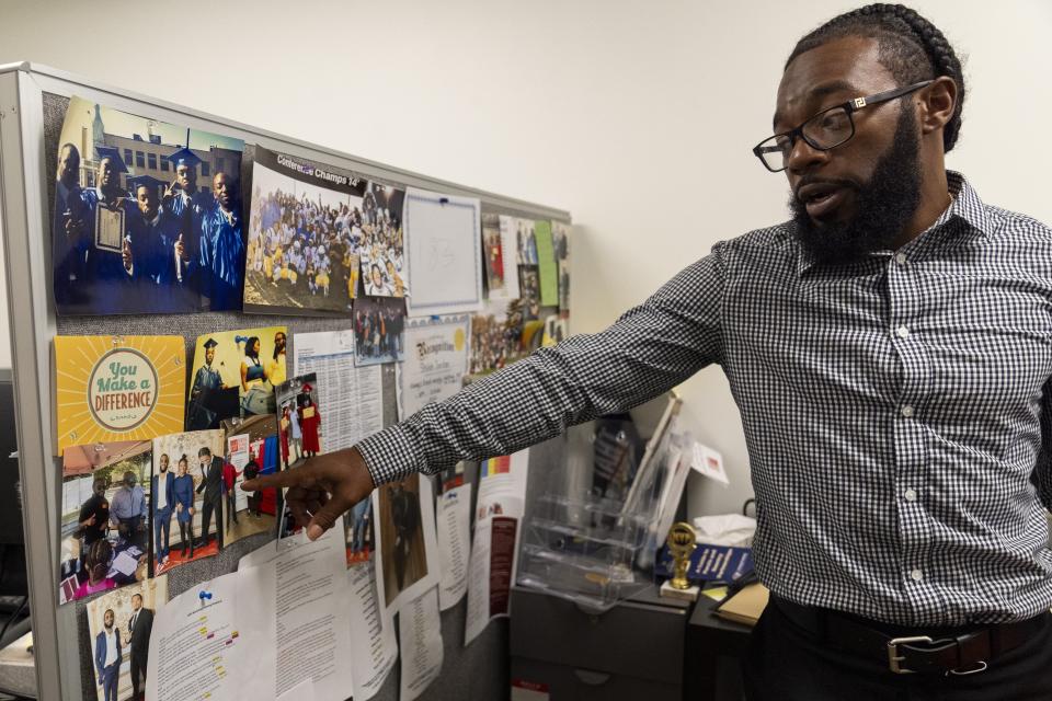 Shiloh Jordan, a Baltimore native whose cannabis conviction was pardoned by an executive order from Maryland Gov. Wes Moore on Monday, points to photos in his office at the Center for Urban Families in Baltimore where he works, Tuesday, June 18, 2024. (AP Photo/Stephanie Scarbrough)