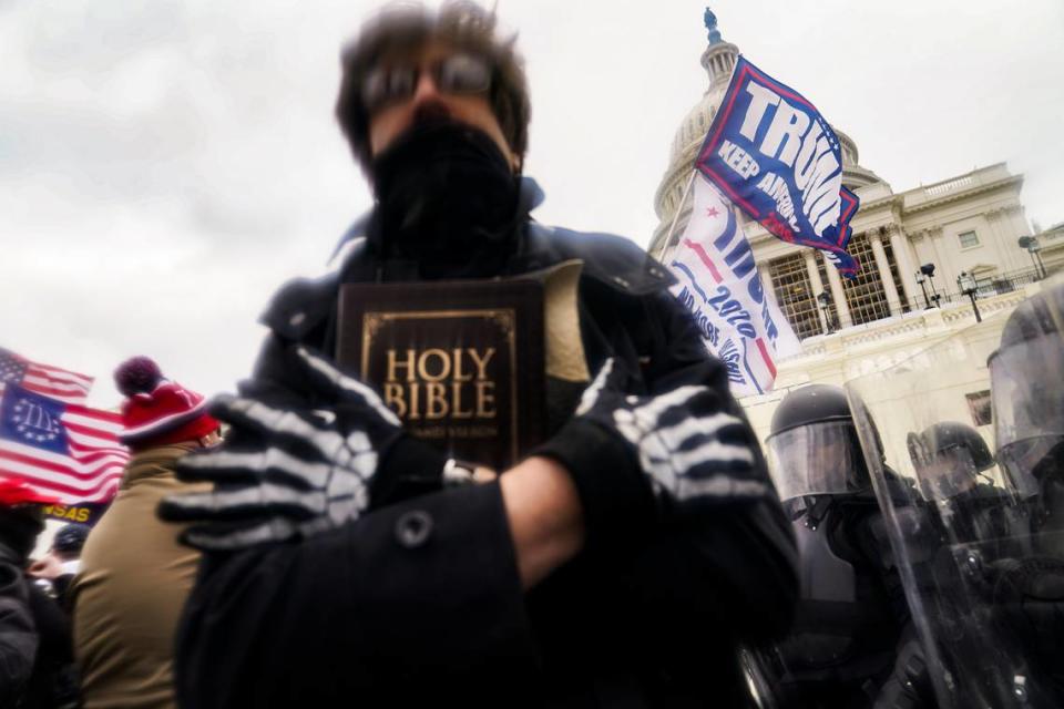 In this Wednesday, Jan. 6, 2021, file photo, a man holds a Bible as Trump supporters gather outside the Capitol in Washington. The Christian imagery and rhetoric on view during the Capitol insurrection are sparking renewed debate about the societal effects of melding Christian faith with an exclusionary breed of nationalism. John Minchillo/AP