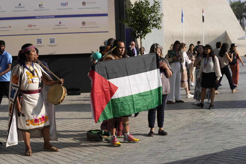 A man holds a Palestinian flag at the COP28 U.N. Climate Summit, Sunday, Dec. 3, 2023, in Dubai, United Arab Emirates. Moments later, authorities asked him to not hold the flag, per regulations on protests. (AP Photo/Rafiq Maqbool)