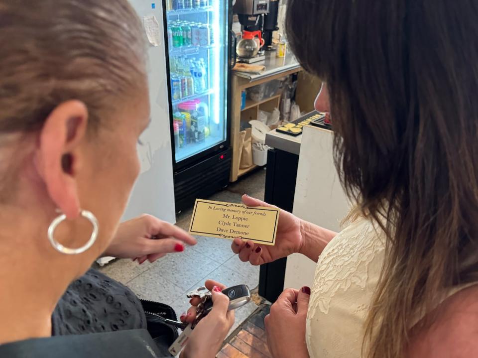 Michelle Strum (right) shows Lillian Loppie-Benjamin the plaque made in memory of her father and two other regular customers who have passed away,