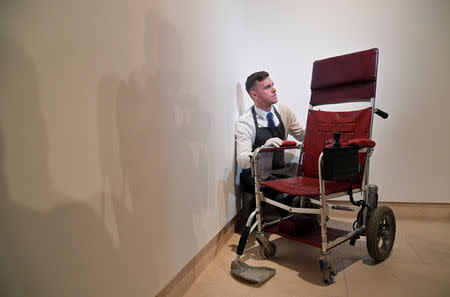 Fine-art handler Tom Richardson poses with a motorised wheelchair belonging to British theoretical physicist Stephen Hawking ahead of an auction of items from Hawkings' personal estate at Christie's in London, Britain October 30, 2018. REUTERS/Toby Melville