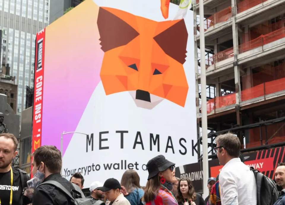 Menschen stehen während einer NFT-Konferenz in New York City vor einer Metamask-Plakatwand am Times Square. - Copyright: Noam Galai/Getty Images