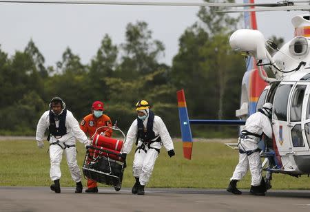 Rescue team members carry the dead body of a passenger of AirAsia flight QZ8501 in a basket at Iskandar airbase in Pangkalan Bun January 6, 2015. REUTERS/Beawiharta