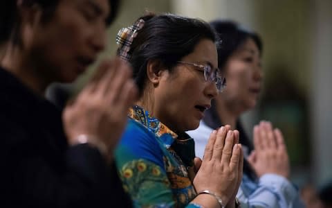 Christians pray during a mass at the South Cathedral in Beijing  - Credit: Nicolas ASFOURI / AFP