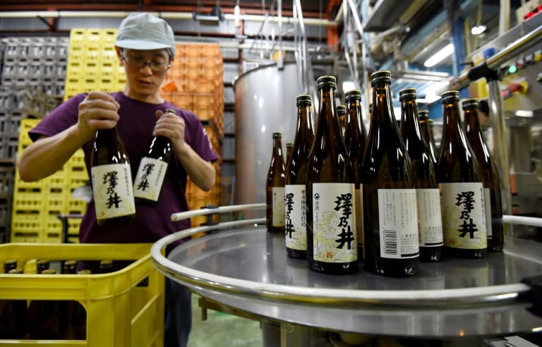 An employee of the Ozawa Shuzo brewery puts bottles of sake into crates