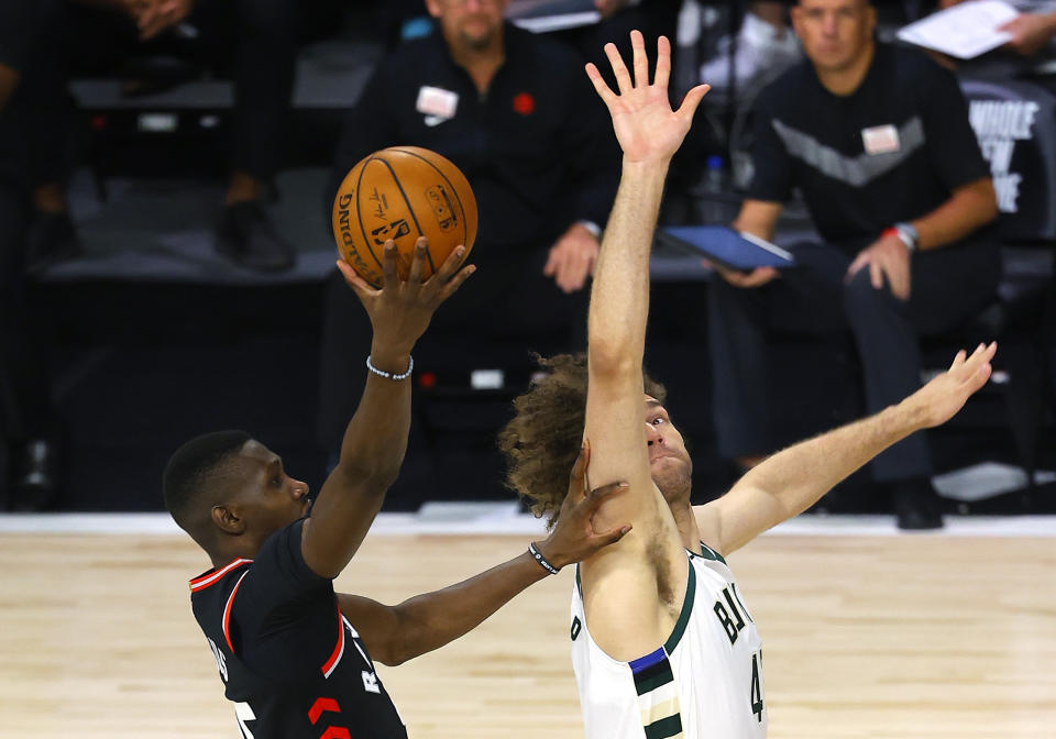 Toronto Raptors' Chris Boucher, left, shoots against Milwaukee Bucks' Robin Lopez, right, during the third quarter of an NBA basketball game Monday, Aug. 10, 2020, in Lake Buena Vista, Fla. (Mike Ehrmann/Pool Photo via AP)