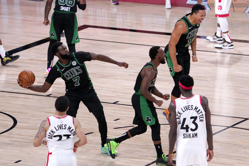 Boston Celtics' Jaylen Brown (7) launches the ball away as teammates Grant Williams, top right, and Kemba Walker, center, react after defeating the Toronto Raptors during an NBA conference semifinal playoff basketball game Friday, Sept. 11, 2020, in Lake Buena Vista, Fla. Raptors' Fred VanVleet (23) and Pascal Siakam (43) look on. The Celtics won 92-87. (AP Photo/Mark J. Terrill)