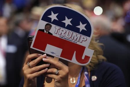 A delegate takes a photograph with her phone as she holds a small sign supporting Republican U.S. presidential nominee Donald Trump during the final day of the Republican National Convention in Cleveland, Ohio, U.S. July 21, 2016. REUTERS/Brian Snyder