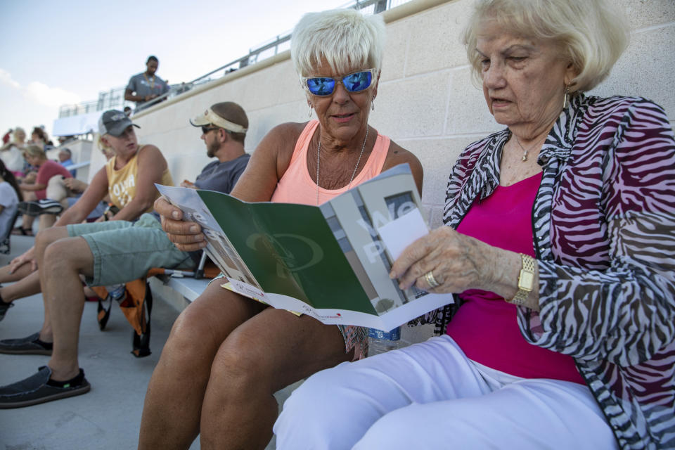 Linda Guthrie, left, and Betty Hughes look at the program during the opening of the new Children's Health Stadium at Prosper ISD on Saturday, Aug. 17, 2019 in Prosper, Texas. Democrats are out to show they’re serious about flipping Texas in 2020 by holding Thursday’s presidential debate in Houston. Republicans are coming off their worst election in Texas in a generation. Fast-changing suburbs are trending more liberal, and Democrats are counting on more left-leaning voters moving in to turn the state blue. But that transformation may not arrive by 2020, and the GOP is closely watching conservative bastions like the booming Dallas suburbs. (AP Photo/Nathan Hunsinger)