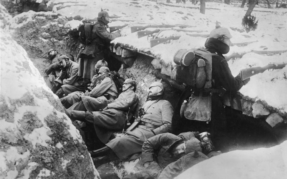 1914: German soldiers sleeping in their trench in the snow as two stand guard with rifles poised, near the Aisne River valley, Western Front, France, World War I.