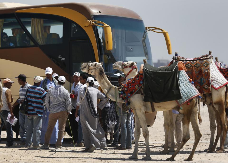 In this Saturday, Sept. 7, 2013 photo, vendors wait for tourists to come down from a bus to offer souvenirs for sale at the historical site of the Giza Pyramids, near Cairo, Egypt. Before the 2011 revolution that started Egypt's political roller coaster, sites like the pyramids were often overcrowded with visitors and vendors, but after a summer of coup, protests and massacres, most tourist attractions are virtually deserted to the point of being serene. (AP Photo/Lefteris Pitarakis)