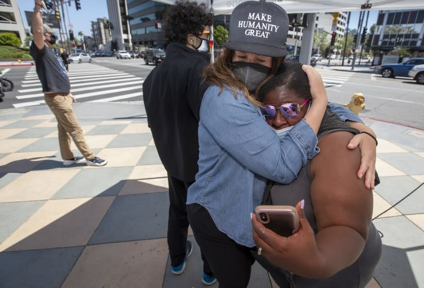 SHERMAN OAKS, CA - APRIL 20: Supporter Katie Mau, left, embraces Latora Green, right, as the verdicts are read in the Chauvin trial on Tuesday, April 20, 2021 in Sherman Oaks, CA. Green has been standing in front of the Sherman Oaks Galleria on Ventura Blvd. and Sepulveda for 325 straight days. (Brian van der Brug / Los Angeles Times)