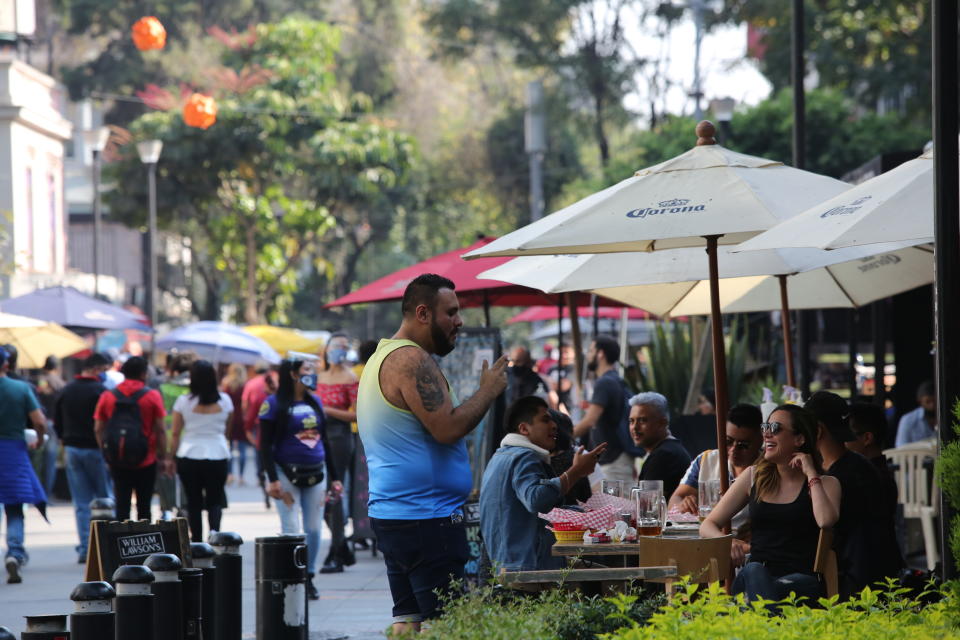 People socialize in the historic center in Mexico City, Saturday, Nov. 14, 2020. Mexico City announced yesterday that restaurants and bars will have to close earlier after the number of people hospitalized for COVID-19 rose to levels not seen since August. (AP Photo/Ginnette Riquelme)