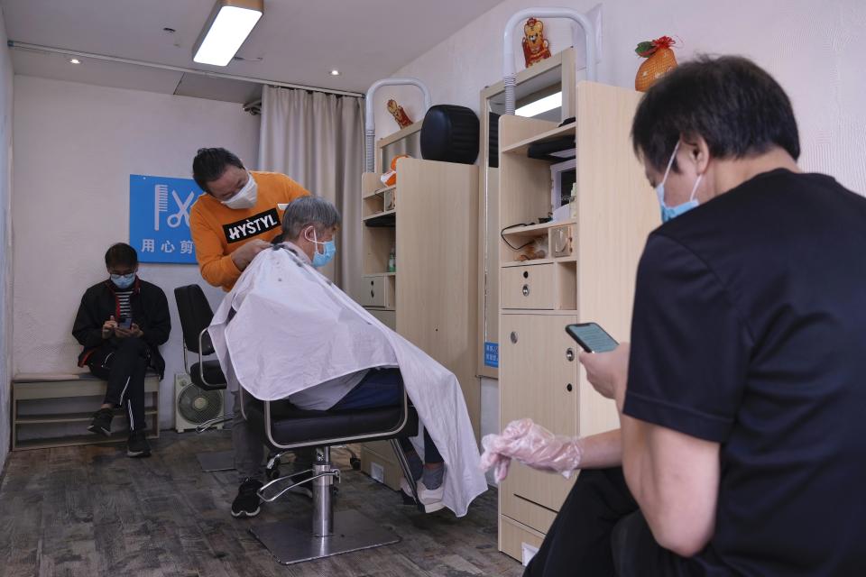 People wearing face masks as a man gets haircut at a salon after temporarily closing in Hong Kong, Thursday, March 10, 2022. (AP Photo/Vincent Yu)