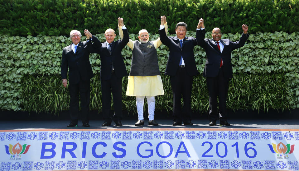 FILE - In this Sunday, Oct. 16, 2016 photo, leaders of BRICS countries, from left, Brazilian President Michel Temer, Russian President Vladimir Putin, Indian Prime Minister Narendra Modi, Chinese President Xi Jinping, and South African President Jacob Zuma raise their hand for a group photo at the start of their summit in Goa, India. Modi and his Bharatiya Janata Party on Thursday, May 23, 2019, claimed a thunderous sweep of India’s general elections, winning well over the 272 seats in the lower house of Parliament required to form a government. Modi’s vision of India is threefold, political analysts say: getting India into the exclusive $5 trillion economy club that includes the European Union, United States, China and Japan; asserting itself as a nuclear power and a force in the world; and placing its Hindu heritage at the center of politics. (AP Photo/Anupam Nath, File)