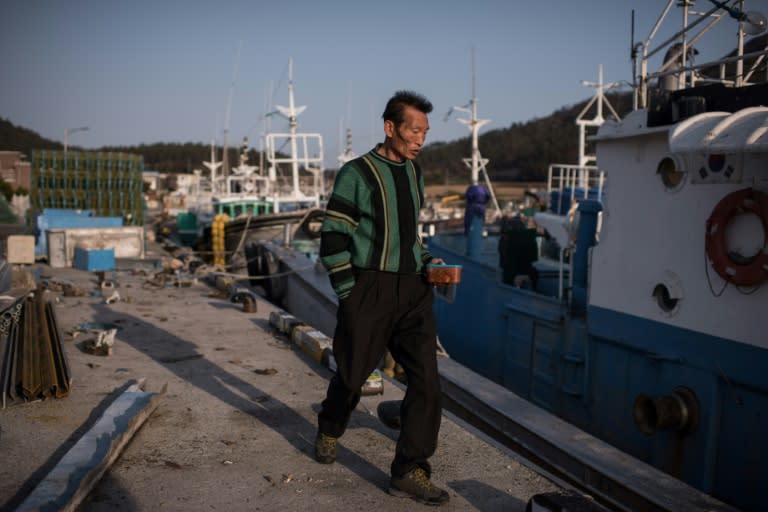 A fisherman walks past boats in a small fishing port adjacent to Paengmok harbour on South Korea's southern island of Jindo