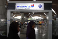 Passengers walk past a signboard of Malaysia Airlines at Kuala Lumpur International Airport in Sepang, outside Kuala Lumpur, Malaysia, Saturday, March 8, 2014. A Malaysia Airlines Boeing 777-200 carrying 239 people lost contact with air traffic control early Saturday morning on a flight from Kuala Lumpur to Beijing, and international aviation authorities still hadn't located the jetliner several hours later. (AP Photo/Lai Seng Sin)