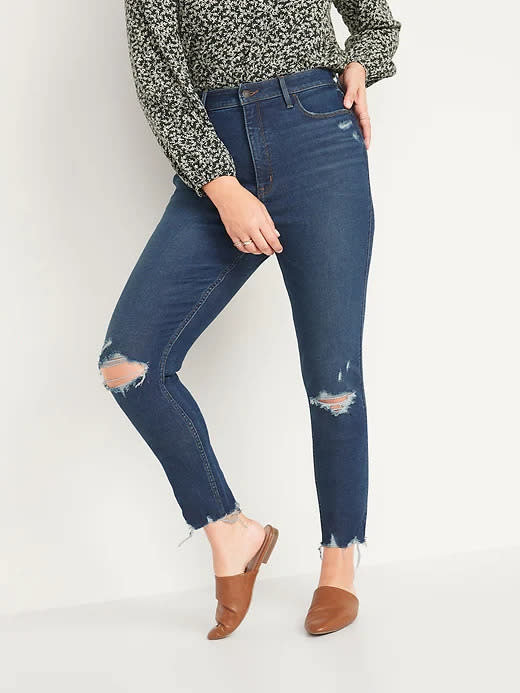 Model wears Extra High-Waisted Rockstar 360° Stretch Super Skinny Ripped Ankle Jeans in dark blue. Image via Old Navy.